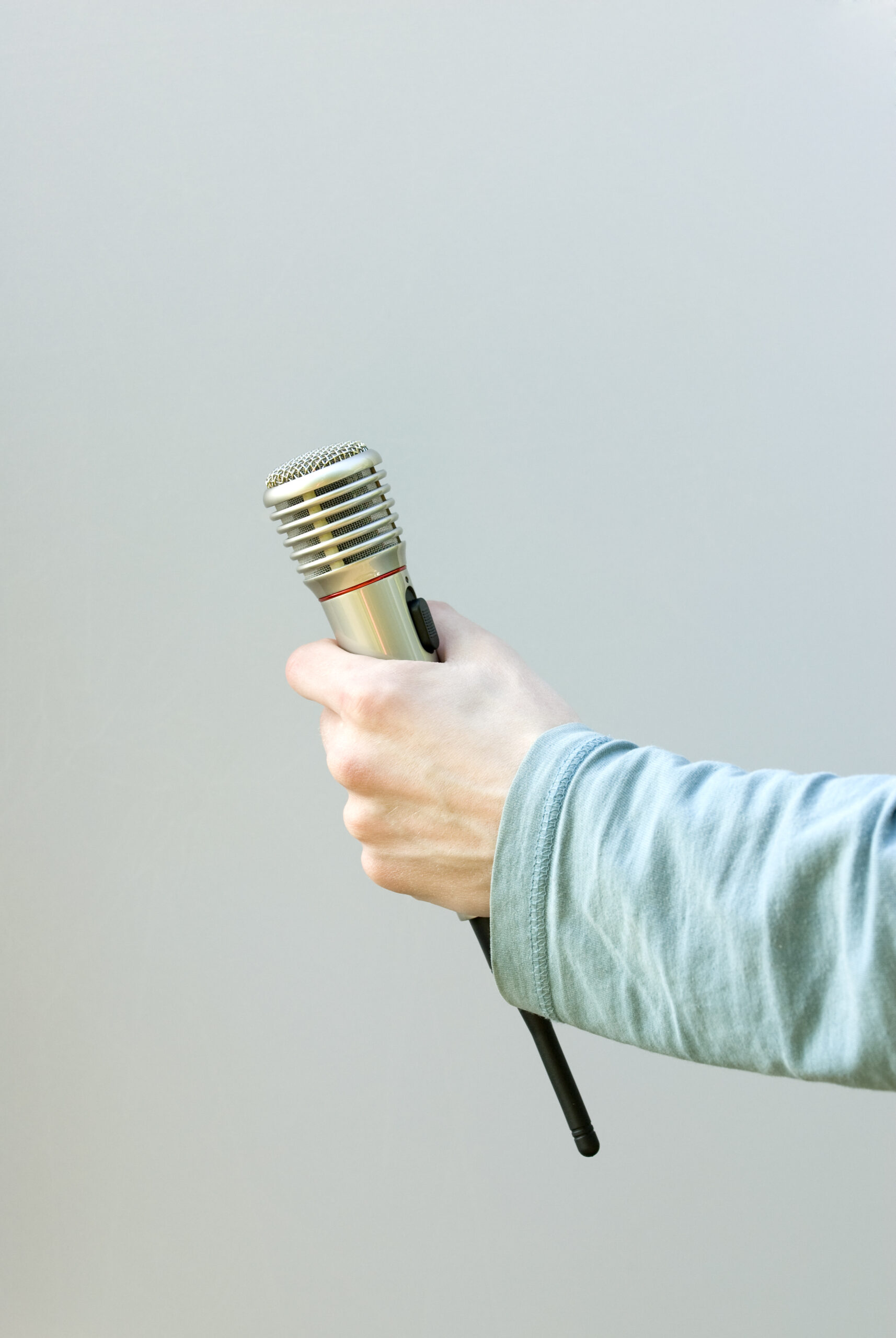 Hand holding radio microphone on gray background